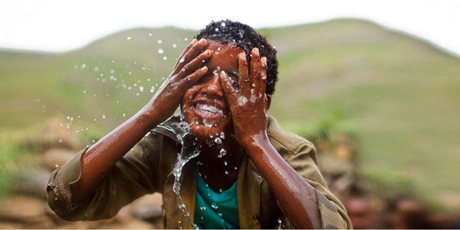 A boy splashes water onto his face