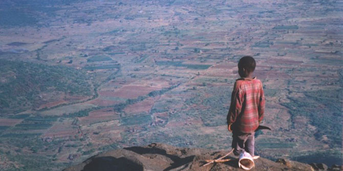 Young boy stand on mountain looking at land below