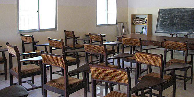 An empty classroom with desks, chairs and a blackboard