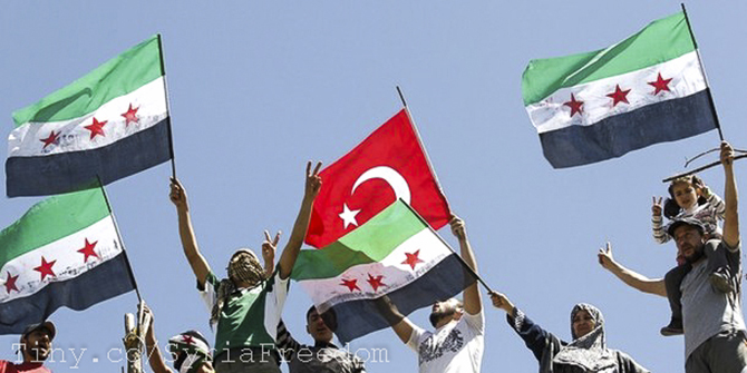 Syrian refugees wave Turkish and Syrian Independence flags during a protest against Assad at Yayladagi refugee camp.