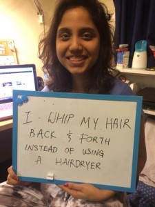 Student holding a whiteboard saying "I whip my hair back and forth instead of using a hairdryer"