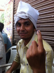 Young man showing his ink-marked finger after voting, May 12 2014